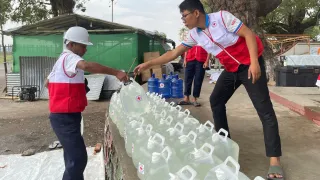 ICRC workers providing clean water containers in Myanmar