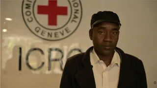 Aly Mubarak, A Sudanese refugee, standing in front of ICRC emblem