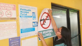 Hospital staff puts up an ICRC-donated poster saying "No weapons allowed"