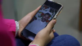 Lana Noamaan holding a smartphone showing a picture of her father