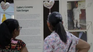 Dos personas son fotografiadas de espaldas mientras observan la exposición Tejer Memoria