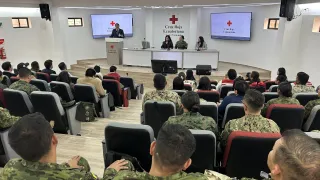 Un auditorio con miembros de las fuerzas armadas y un trabajador del CICR dando unas palabras.