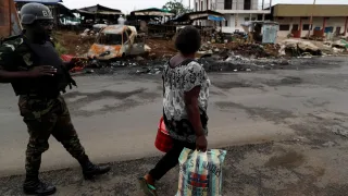 A woman walks past a Cameroonian elite Rapid Intervention Battalion (BIR) member in the city of Buea in the anglophone southwest region, Cameroon 