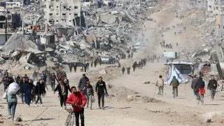 Palestinians walk in a street in Jabalia along the rubble of destroyed buildings as the displaced head to the northern areas of the Gaza Strip, on the third day of a ceasefire deal in the war between Israel and Hamas, on January 21, 2025.