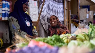 Una colaboradora del CICR y conversa y sonríe junto a una mujer. 