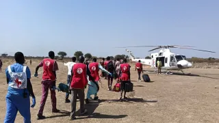 A group of South Sudan Red Cross volunteers, accompanied by an ICRC health personnel, carrying a weapon-wounded patient on a stretcher towards an evacuation aircraft to be airlifted for further treatment. Photo Credit Greta Mancassola/ICRC.