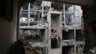 Vista de un edificio colapsado y en ruinas en Nowruz,Irán., observado a través de un gran agujero en la pared. La estructura de concreto y metal está gravemente dañada, con pisos derrumbados y escombros esparcidos.a-Reuters-Connect.