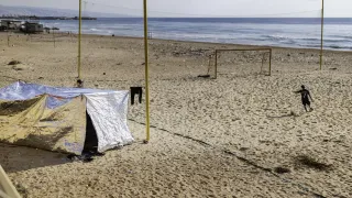 A boy plays football on the beach along the Corniche in Beirut, Lebanon, on March 7, 2026, next to a tent set up by a displaced family who had to move from Beirut’s southern suburbs following an evacuation order issued by Israel.