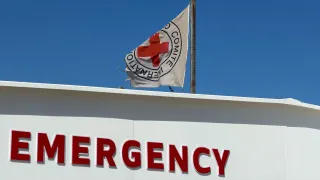 The ICRC flag flies above the emergency entrance of the Gaza Red Cross Field Hospital in Rafah, with signage in English and Arabic against a clear blue sky.