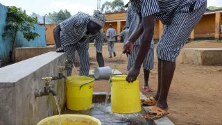 Inmates at a Prison in Kenya fetching clean water following a successful water systems upgrade by the Nairobi Regional Delegation.