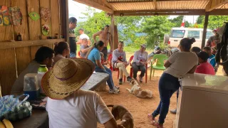 Personas de una comunidad rural en Colombia están sentadas en grupo mientras conversan con representantes del Comité Internacional de la Cruz Roja (CICR), en un entorno comunitario.