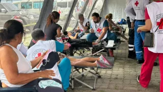 People receive medical care from Venezuelan Red Cross volunteers at a temporary outdoor treatment area following the June 2026 earthquakes in Venezuela. Several patients rest on folding stretchers while volunteers provide first aid and medical assistance.