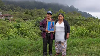 Un hombre y una mujer sostienen la fotografía de un familiar desaparecido.