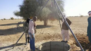 Ghataye. Des hommes observent les travaux de fonçage d'un puits.