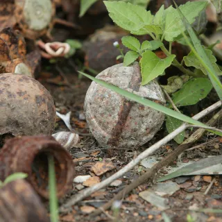 ICRC_Xieng Khouang province. Piles of rusted war material including bombs, mortars, and unexploded submunitions lay in a field near a metal foundry. Photographer : HOLMES, JIM