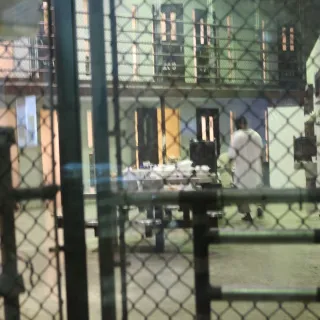  Guantanamo Bay, United States detention facility, Camp 6. The bulk of the detainees live in Camps 5 and 6. This image, taken from outside a communal cell block in Camp 6, shows a detainee with his back towards the door.