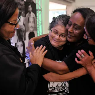 Familiares de pessoas desaparecidas se abraçam em um evento.