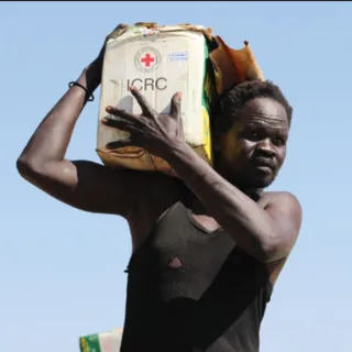 Man carries a water tank with an ICRC logo on it on his shoulder