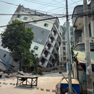 Un edificio de varios pisos se inclina peligrosamente tras un fuerte terremoto en Myanmar, con escombros e infraestructuras dañadas visibles en primer plano.