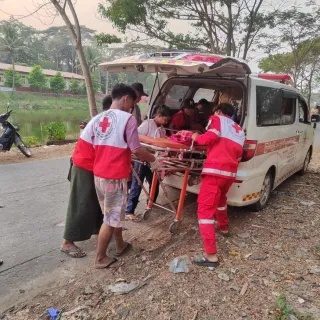 Un equipo de emergencia de la Cruz Roja de Myanmar carga a un herido en una camilla dentro de una ambulancia tras el terremoto de Myanmar, prestando ayuda médica urgente.