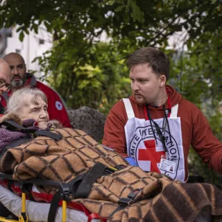 Mykolaiv. An ICRC staff member is talking to an old lady while she is being transferred to a new specialized facility.