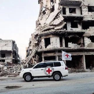 ICRC car next to buildings that have been destroyed by conflict 