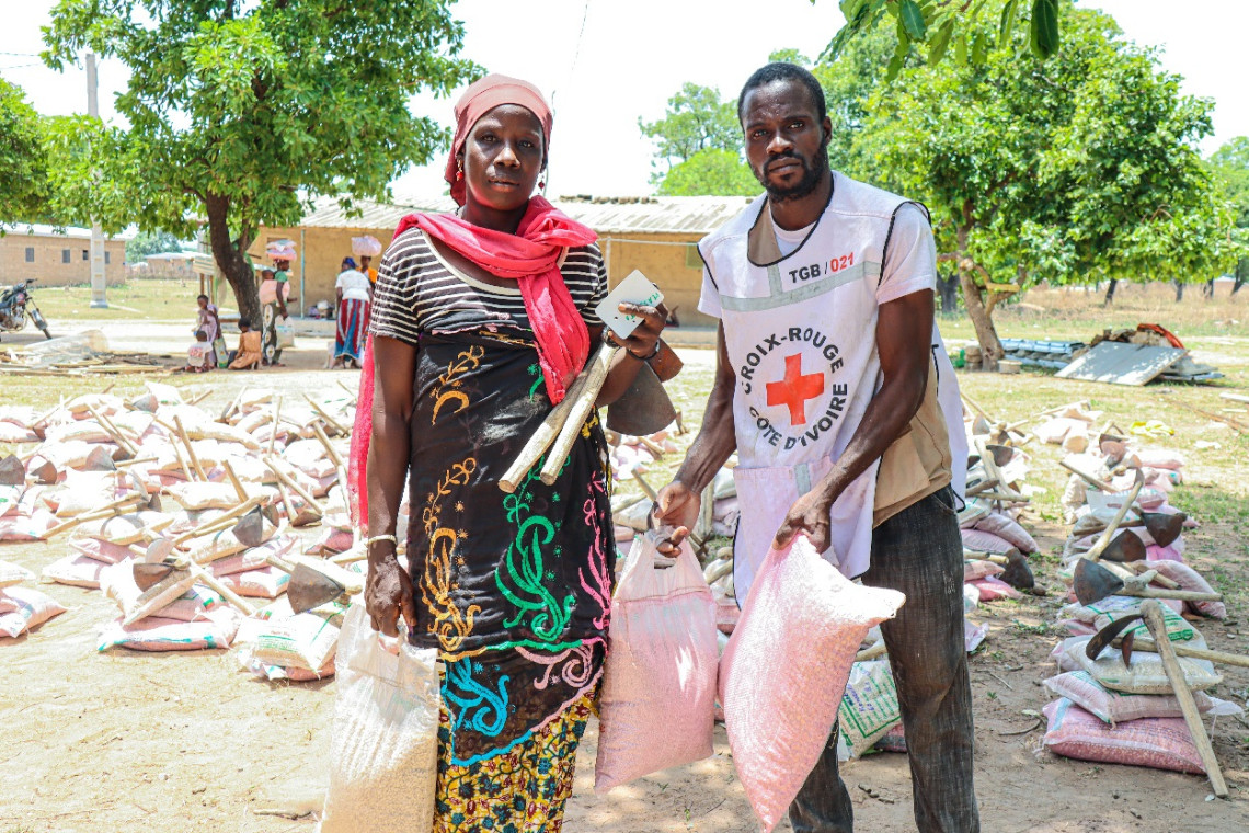 Une bénéficiaire en compagnie d'un volontaire de la Croix-Rouge ivoirienne. Yapo Ange-Eustache AGBE / CICR