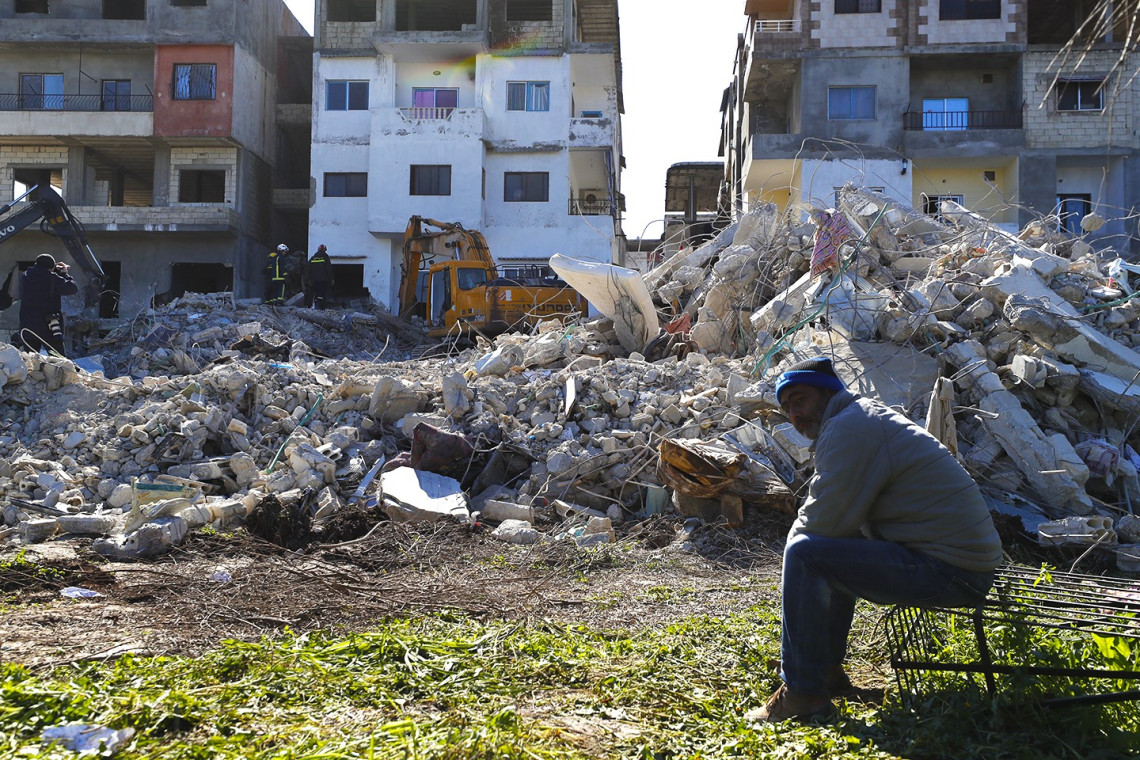 رجل يجلس في موقع تأثر بالزلزال في مدينة جبلة - اللاذقية. Photo: Omar Sanadiki/ The Associated Press