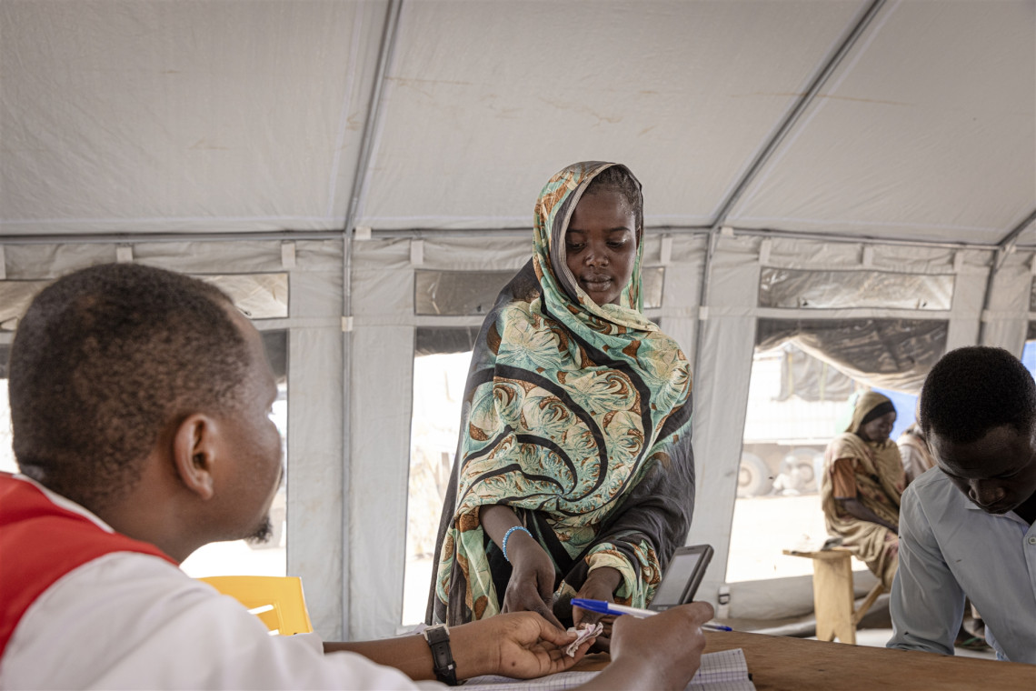 Zuhal remet un morceau de papier contenant le numéro de téléphone de son oncle à un volontaire de la Croix-Rouge. Elle utilise le service téléphonique de la Croix-Rouge pour joindre son oncle qui vit à Gedaref, dans l’est du Soudan. Elle espère partir vivre chez lui, mais pour l’instant, ses appels n’ont pas abouti.