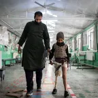 Man walking with boy with a prosthetic leg at rehabilitation center.