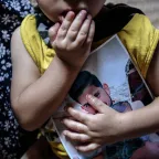 Child holds picture of missing family member. 