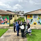Jóvenes vestidos en un juego de roles interactúan en un jardín frente a unos murales.