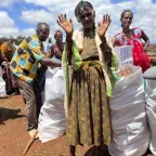 Woman at Ethipoian Red Cross Society distribution of food supplies and essential household items waves to the camera
