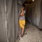 Child next to a tent in ICRC camp in Greece