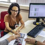 Três mulheres folheiam uma publicação em um escritório; uma delas exibe o logotipo do CICV.