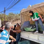 ICRC worker stands at the back of a lorry to unload blankets and essential items