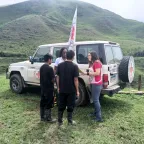 Cuatro personas reunidas, al lado de una camioneta del CICR y en medio de una montaña.