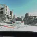 ICRC Landcruisers driving past fallen buildings
