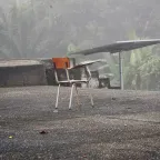 Una silla en medio de un patio, como abandonada, y atrás se ve un contexto de zona rural