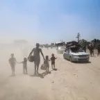 A father with his 4 children walking in an area full of sand