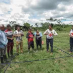 Habitantes de una zona rural participan en una actividad colectiva, en la que sostienen una cuerda entrelazada que forma una red simbólica. El ejercicio se realiza en compañía de integrantes del CICR.