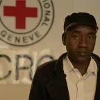 Aly Mubarak, A Sudanese refugee, standing in front of ICRC emblem
