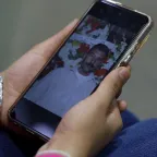Lana Noamaan holding a smartphone showing a picture of her father