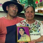 Dos personas sostienen el retrato de su hija desaparecida