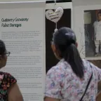 Dos personas son fotografiadas de espaldas mientras observan la exposición Tejer Memoria