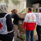 Iran humanitarian needs ICRC and Red Crescent staff unload boxes of humanitarian supplies from a truck, working together to deliver aid.