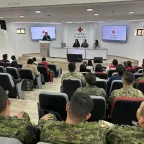 Un auditorio con miembros de las fuerzas armadas y un trabajador del CICR dando unas palabras.