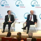 The panelists sit on stage at the Paris Peace Forum, engaged in discussion. They are seated on white chairs in front of a backdrop displaying the Paris Peace Forum logo. The audience is visible in the foreground.
