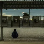 Man sitting in front of a row of public telephones