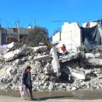 A little girl carrying a bag of supplies walks past destroyed buildings in Rafah, Gaza